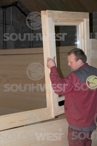 Window being inserted into the log cabin wall